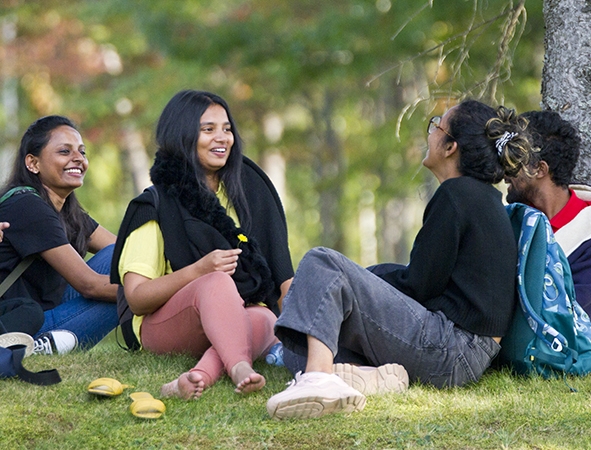A group of international students sitting in a forested area on Nipissing University Campus.