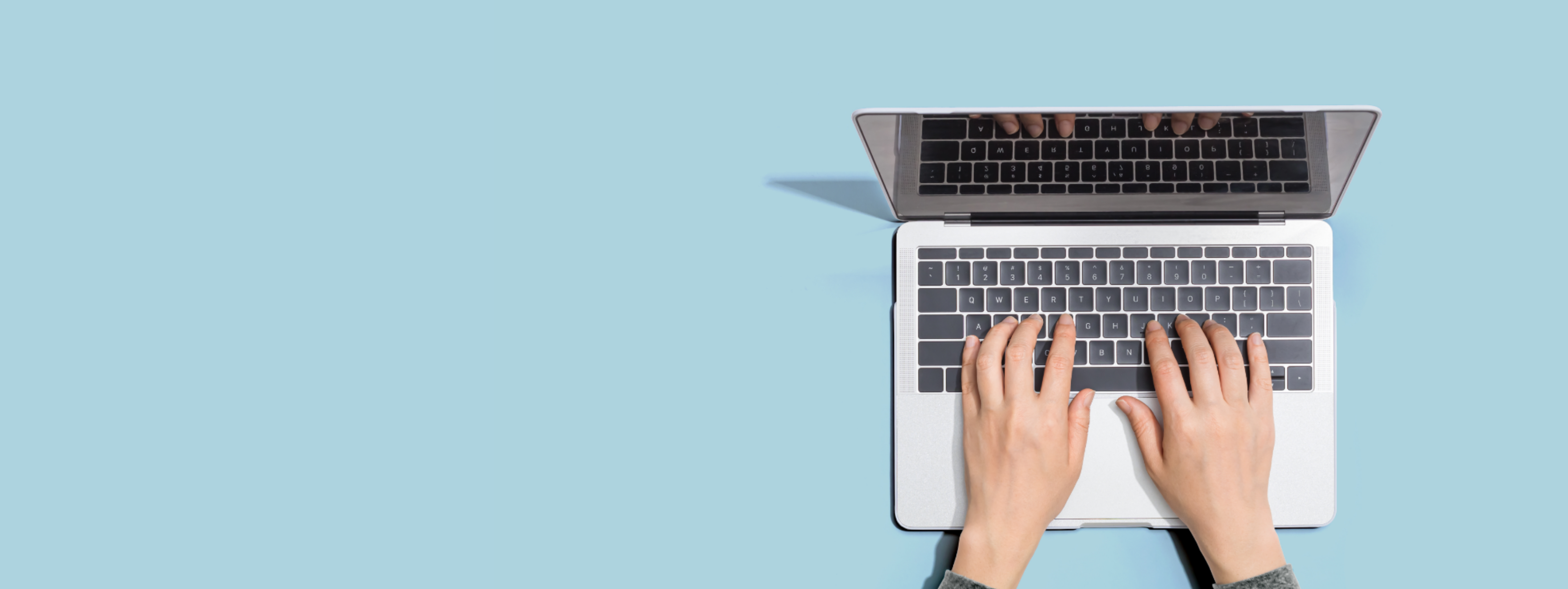 Hands typing on a laptop with a blue background behind