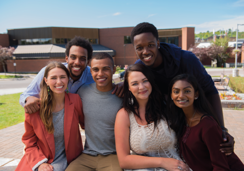 A group of students posing in front of the school