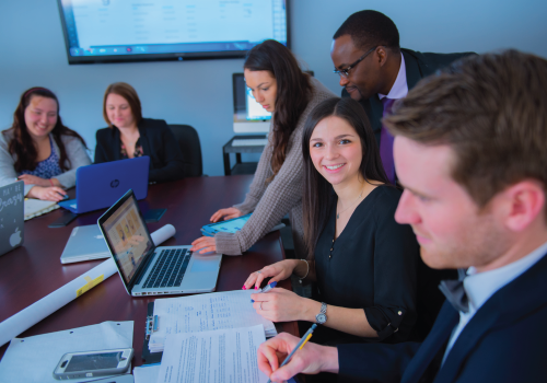 A group of students surrounding a laptop