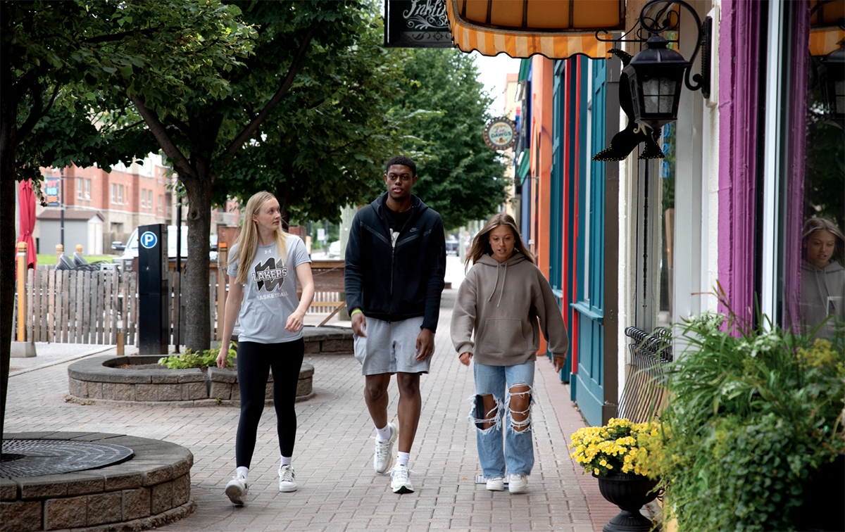 3 students walking on a street with colorful buildings