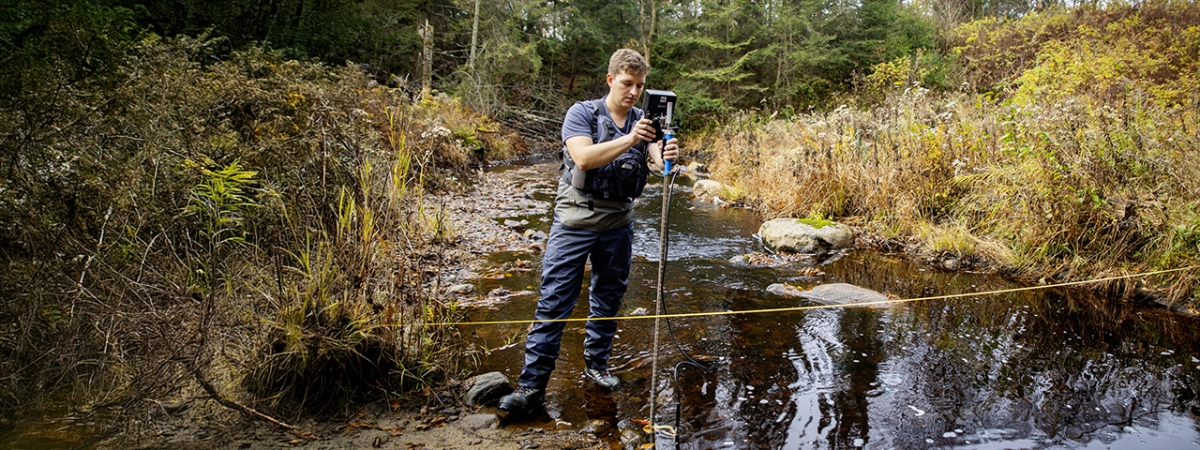 A male student setting up an experiment at a pond