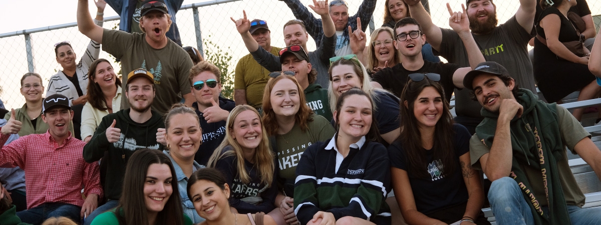 Homecoming attendees cheering from the bleachers