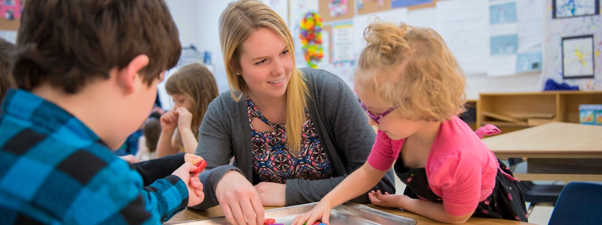 A teacher playing games with a child in pink