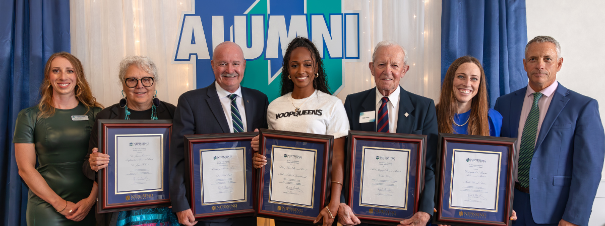 The 2024 Alumni Award recipients stand with their awards.