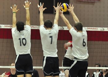 Photo of volleyball players blocking at the net