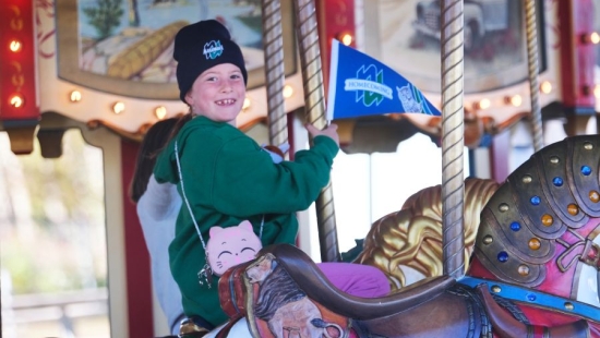 A boy in Nipissing University swag enjoying a carousel ride
