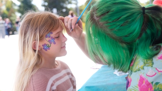 Young girl is getting a face painting during NU Homecoming 2025