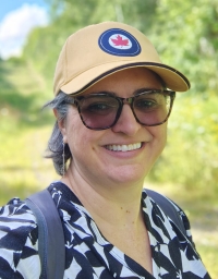 A woman wearing a cap taking a picture against a nature background