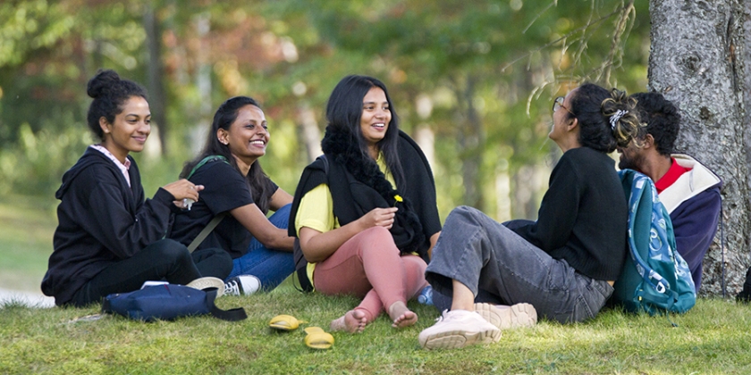 A group of international students sitting in a forested area on Nipissing University Campus.