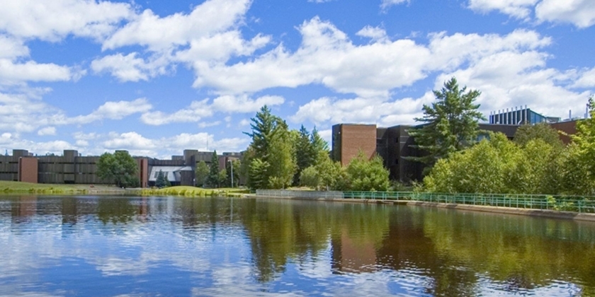 Blue cloudy sky reflecting on the pond at Nipissing University